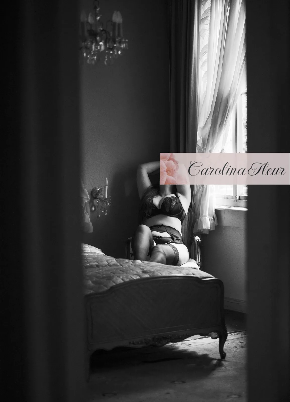 Carolina Fleur in Dessous auf einem Bett unter einem Kronleuchter, Blick durch eine offene Tür