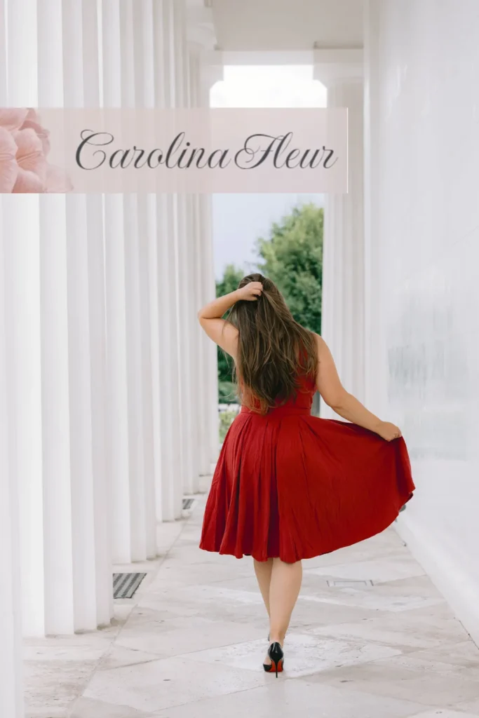 Carolina Fleur im roten Kleid in einem hellen Säulengang, Rückenansicht