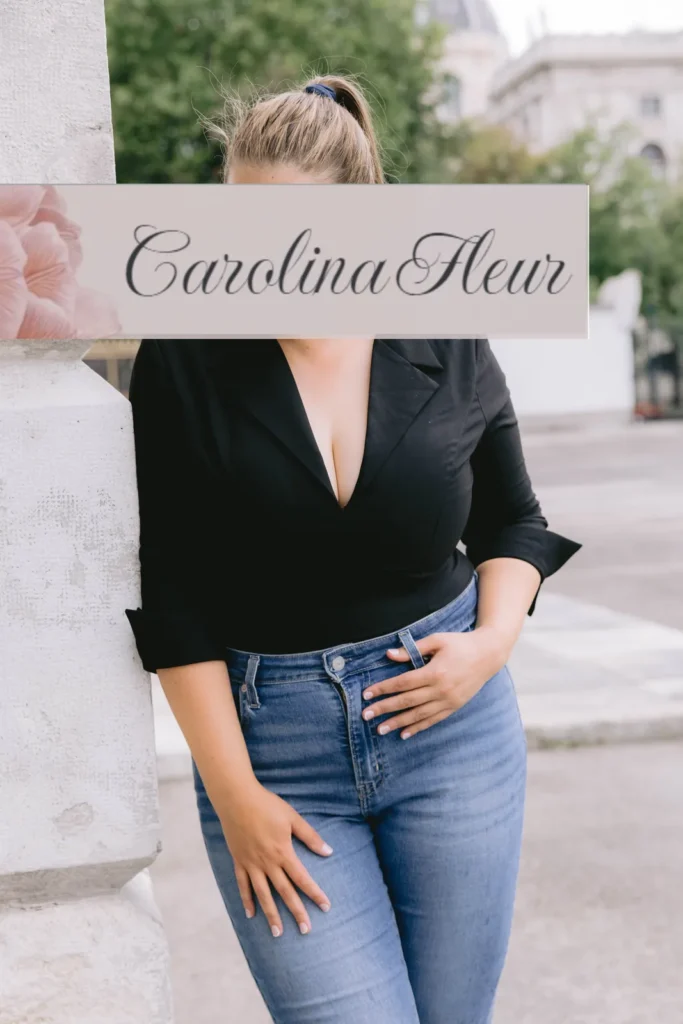 Carolina Fleur in schwarzer Bluse und Jeans an einer Säule in der Stadt