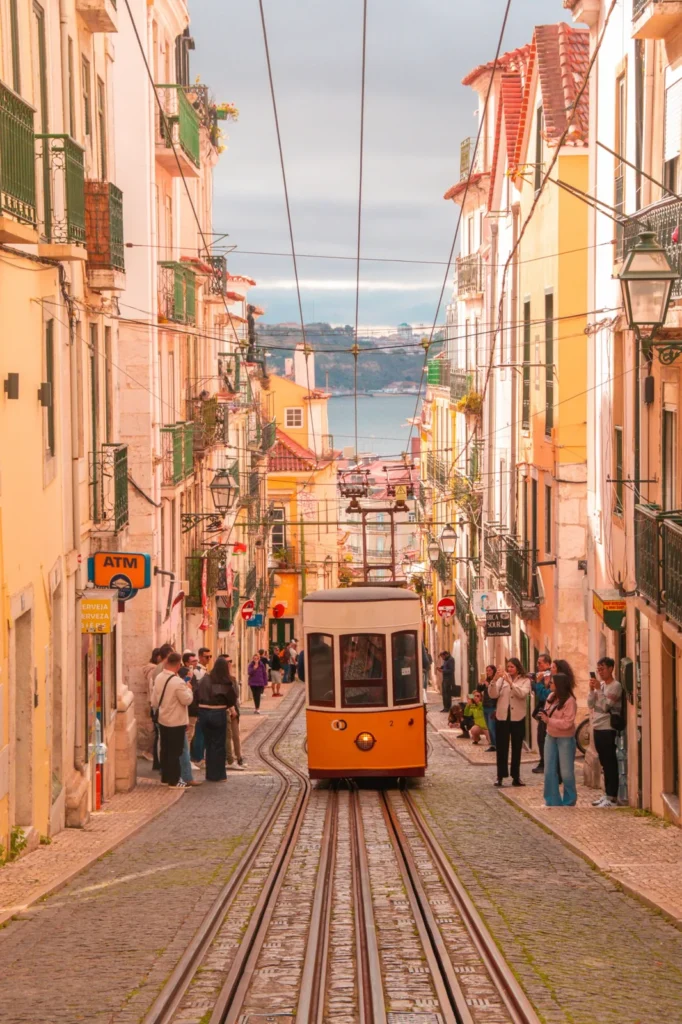 Gelbe Standseilbahn Elevador da Bica in einer Altstadtgasse von Lissabon mit Blick auf den Tejo
