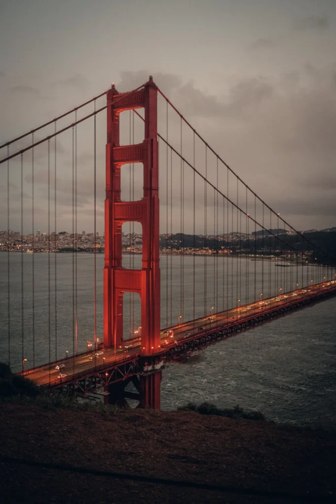 Golden Gate Bridge in San Francisco in der Abenddämmerung, mit beleuchteter Fahrbahn und der Stadt im Hintergrund